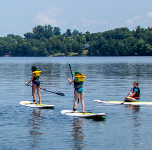 Three youths learning to stand up paddle board.